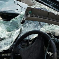 view from inside of car in driver's seat with broken windows 