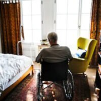 man in a wheelchair looking out a window