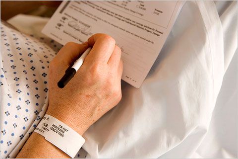 Person in a hospital bed signing a paper