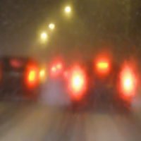 blurry image with cars driving in front with brake lights flashing