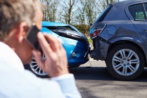 Man calling someone looking at a car accident