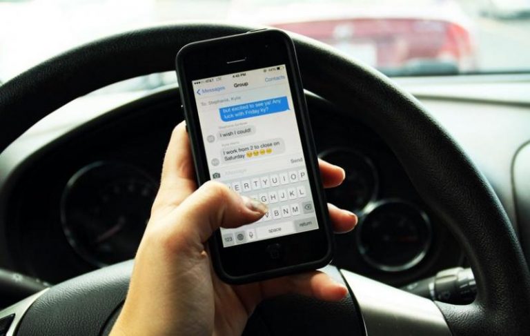 a hand holding a phone in a car