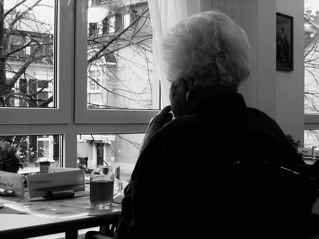 Elderly woman looking outside of a window