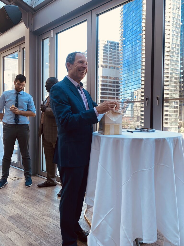 a person in a suit standing next to a table with a glass of wine