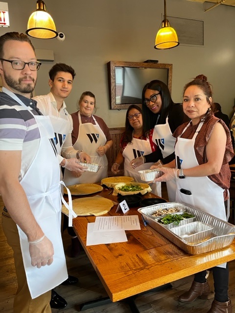 a group of people standing around a table with food on it