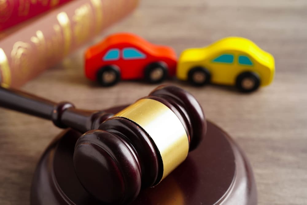 Gavel and two toy accident cars in backround.