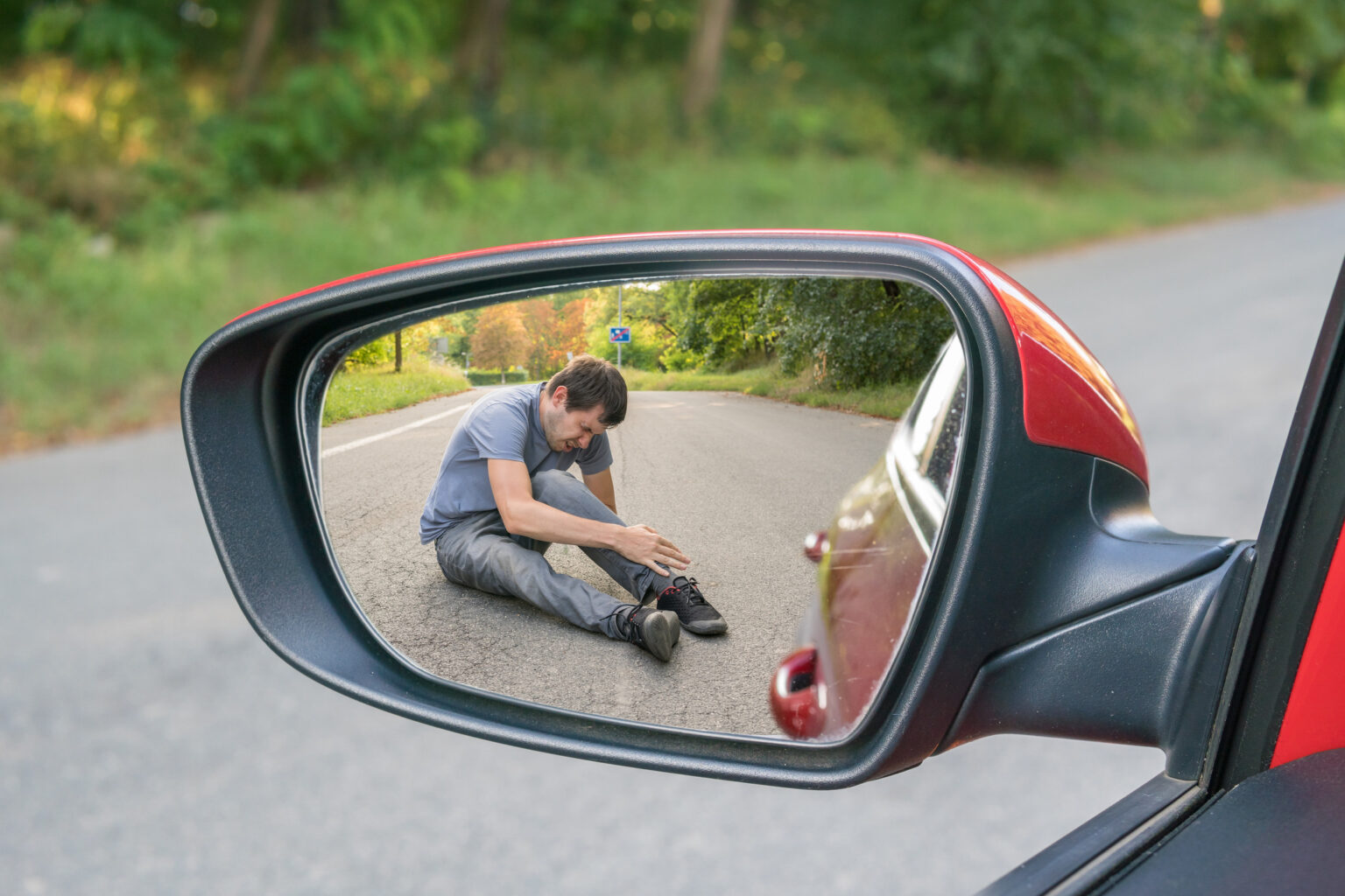 Hit and run concept. View on injured man on road in rear mirror of a car.