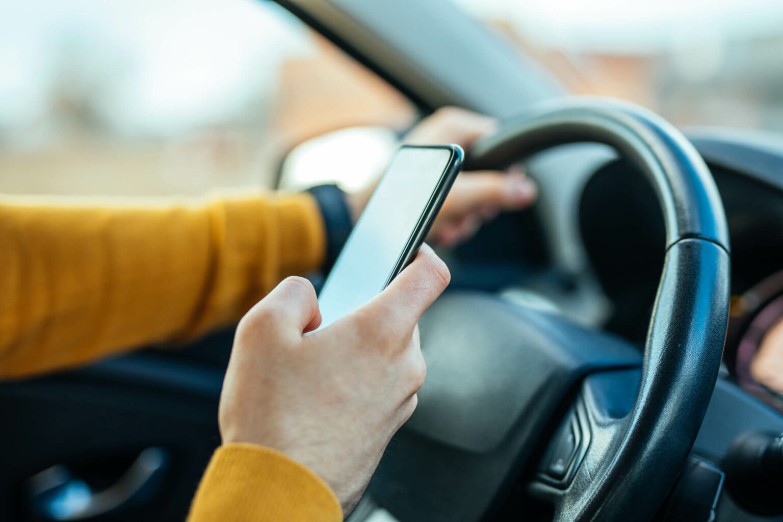 a hand holding a phone in a car