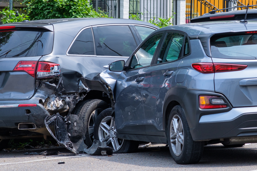 Two cars tangled in collision with drivers discussing, showing complexity of determining fault in accidents.
