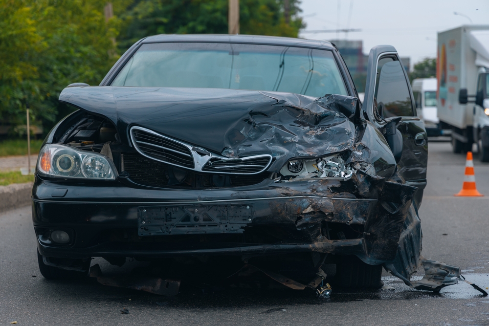 Driver photographs rear bumper damage after accident, preparing to file an insurance claim on the scene.
