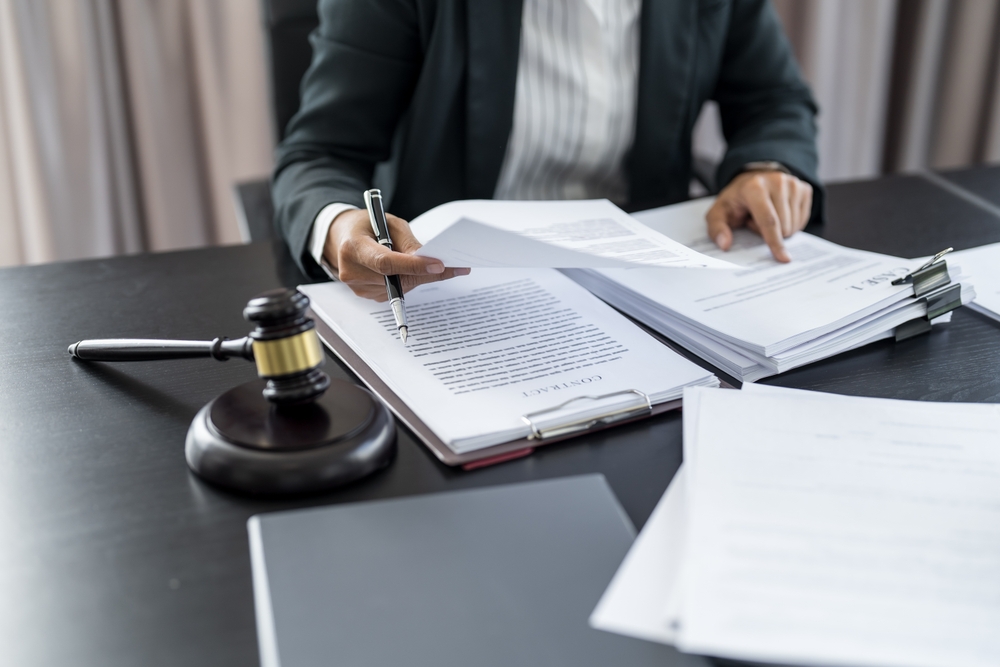 Stressed driver looks at clock while ignoring legal papers, risking delays in filing a car accident claim.
