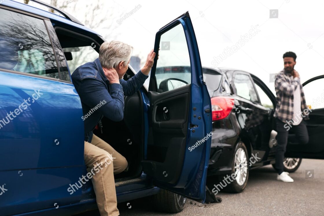 Two male drivers inspect damage after a rear-end crash, highlighting typical fault disputes in such collisions.