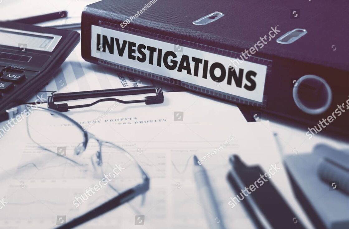 Ring binder labeled “Investigations” on desk with reports and glasses, symbolizing steps taken after a road rage incident.