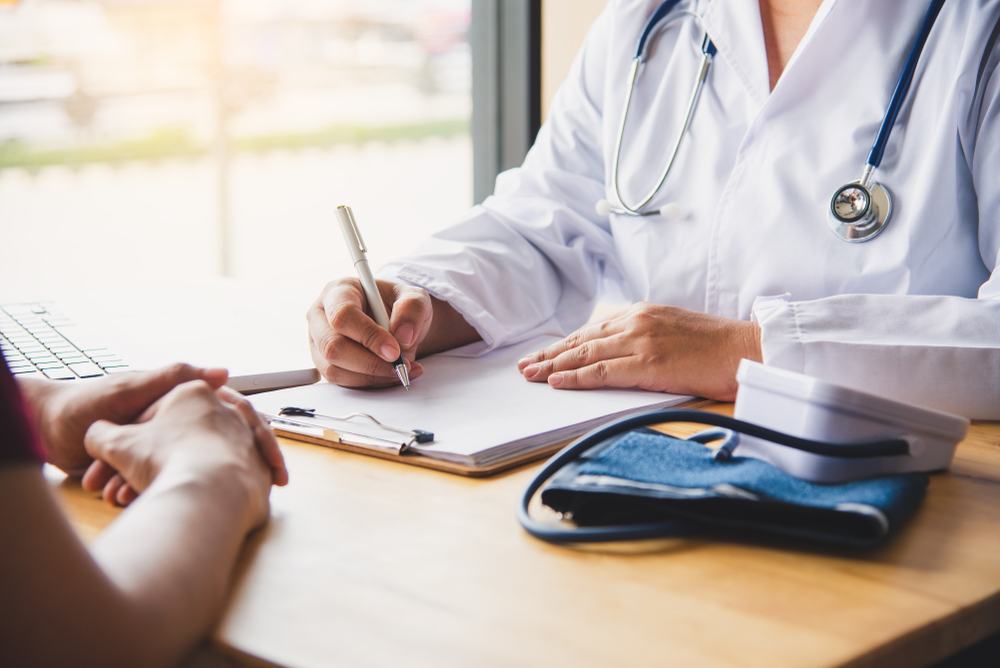 Close up of a doctor filing paperwork across a desk from a patient