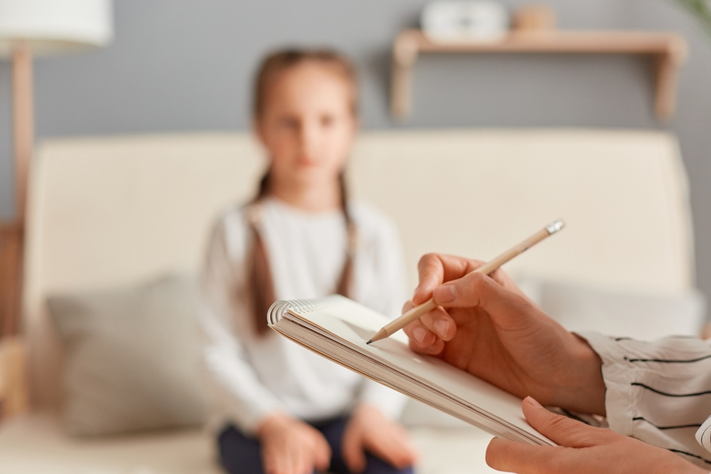 Image a child in blurred background speaking to a counselor